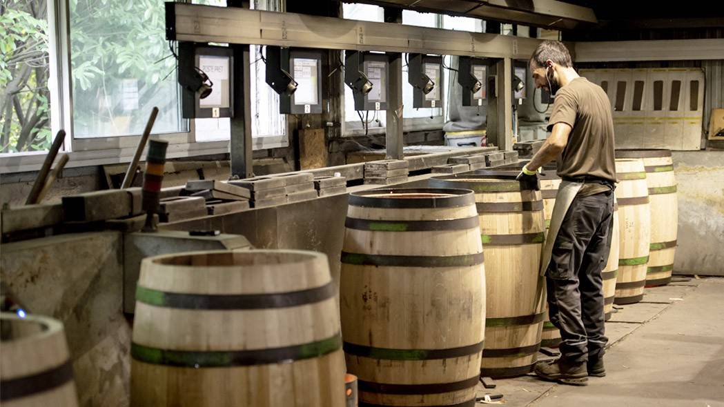 Rangée de barriques en cours de chauffe sur les brasiers de l'atelier de la Tonnellerie Baron, un tonnelier au travail