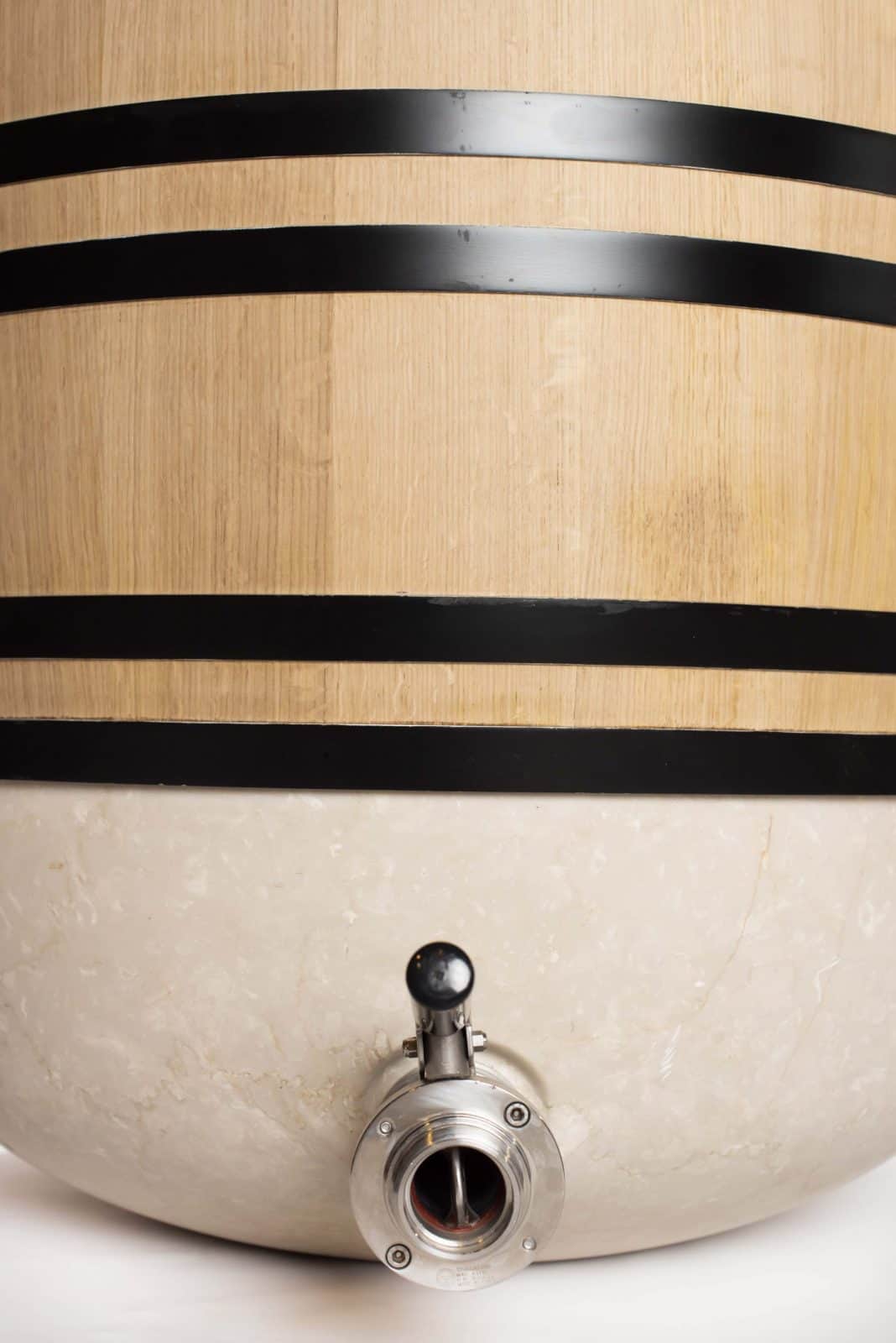 Détail de la cuve ALMA : douelles de chêne cerclées de noir posées sur une base en céramique, avec vanne inox